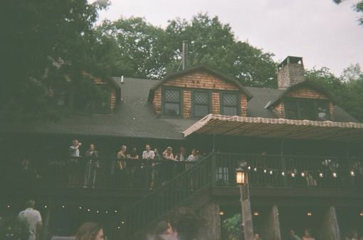 A group of people are standing outside of a large house.
