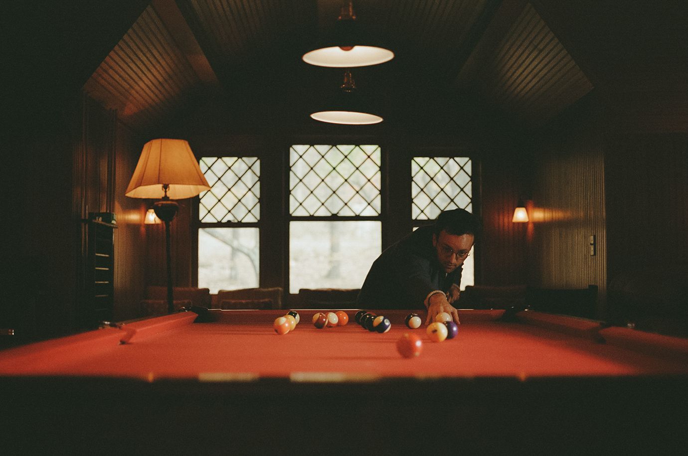 A man is playing pool in a dark room