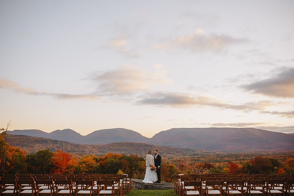 A bride and groom are standing in front of a mountain range at their wedding.