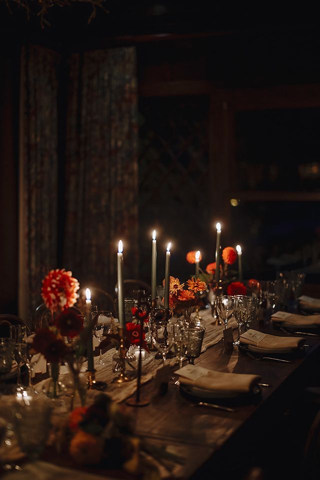 A long table with candles and flowers on it in a dark room.