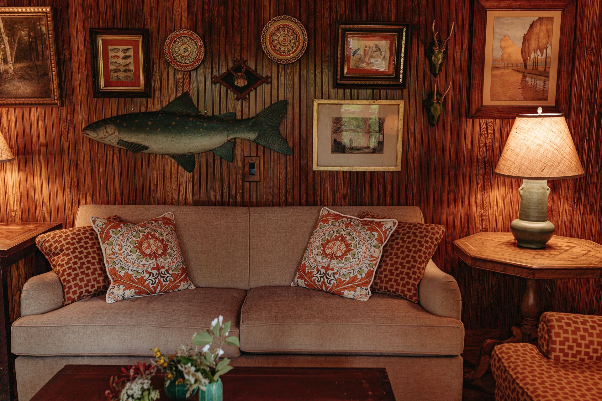 A living room with a couch , chairs , lamps and a fish on the wall.