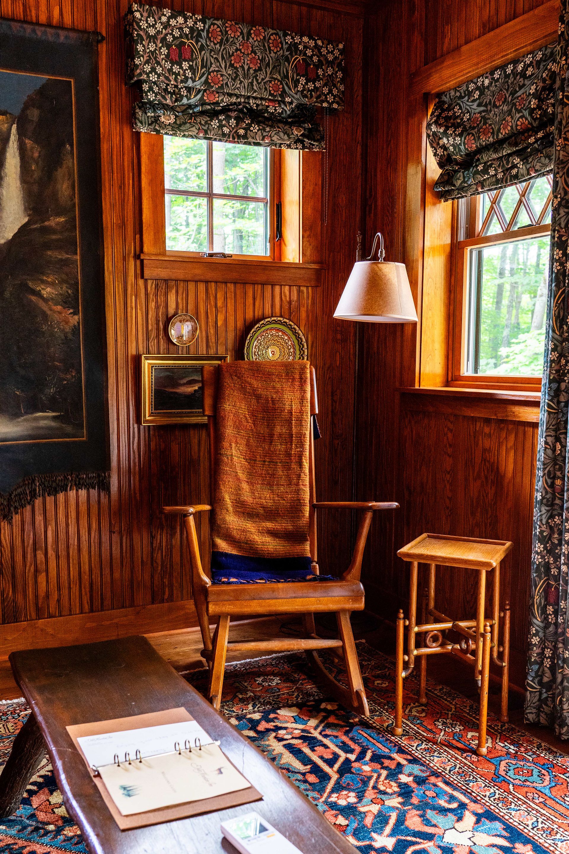 A living room with a rocking chair and a lamp.