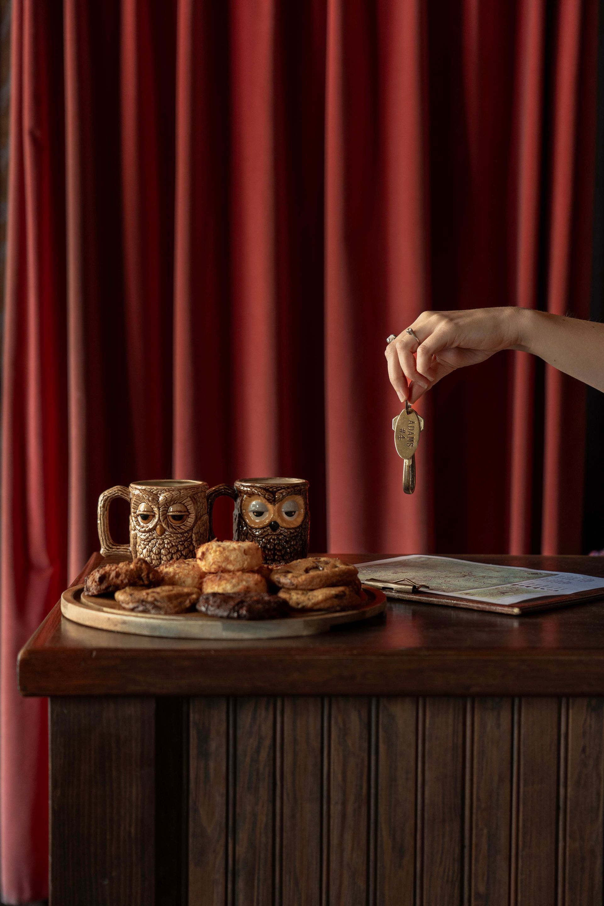 A person is holding a key in front of a tray of donuts on a table.