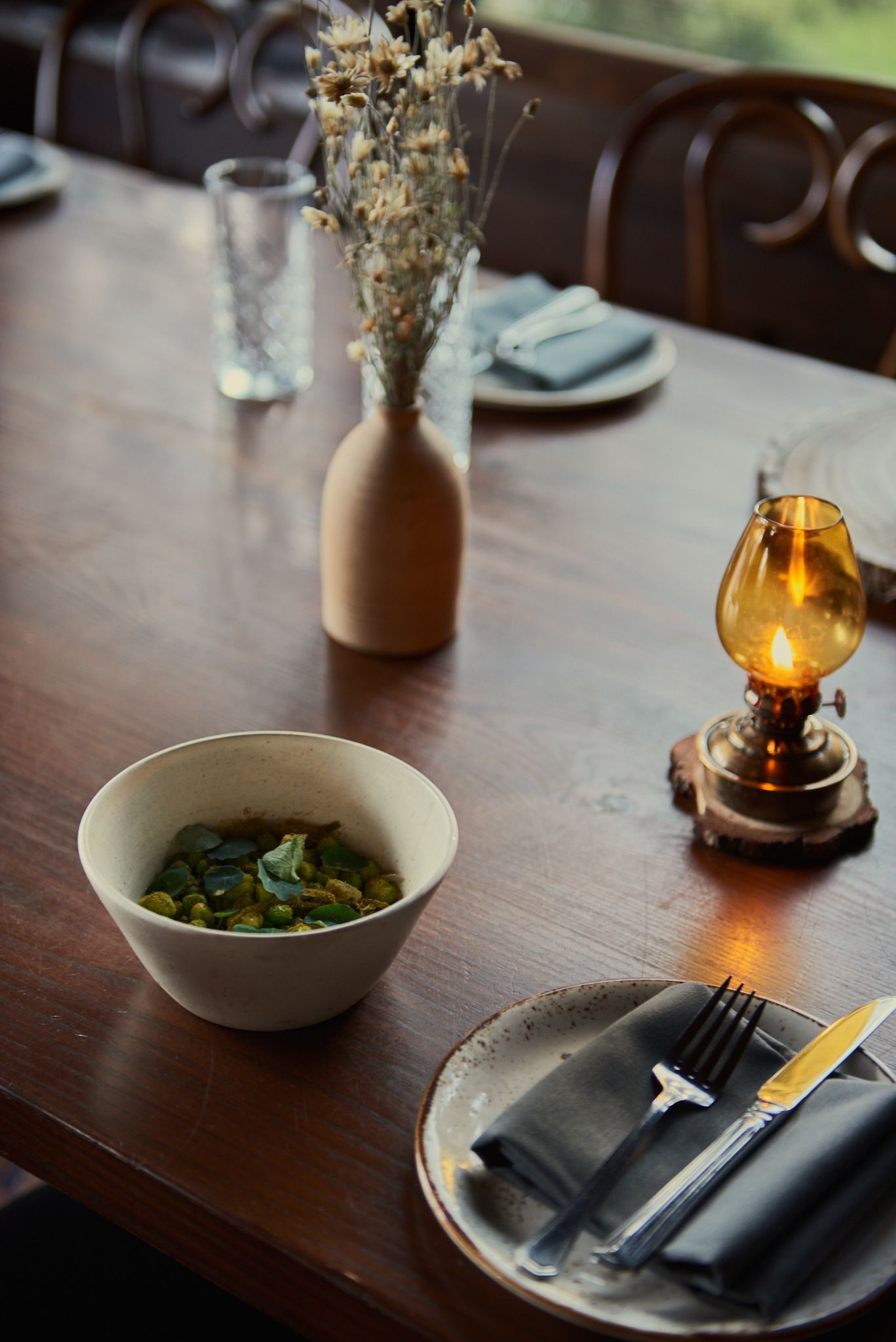 A wooden table with a bowl of food and a lamp on it.