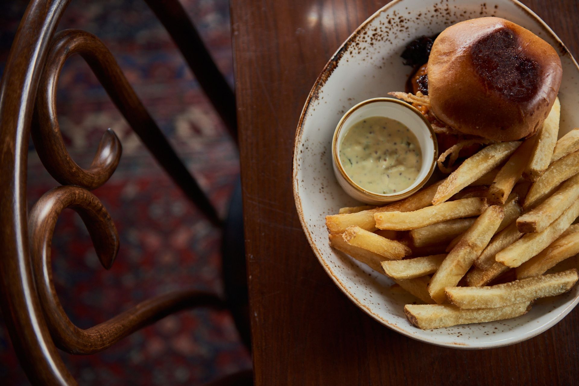 A plate of food with a hamburger and french fries on a table.