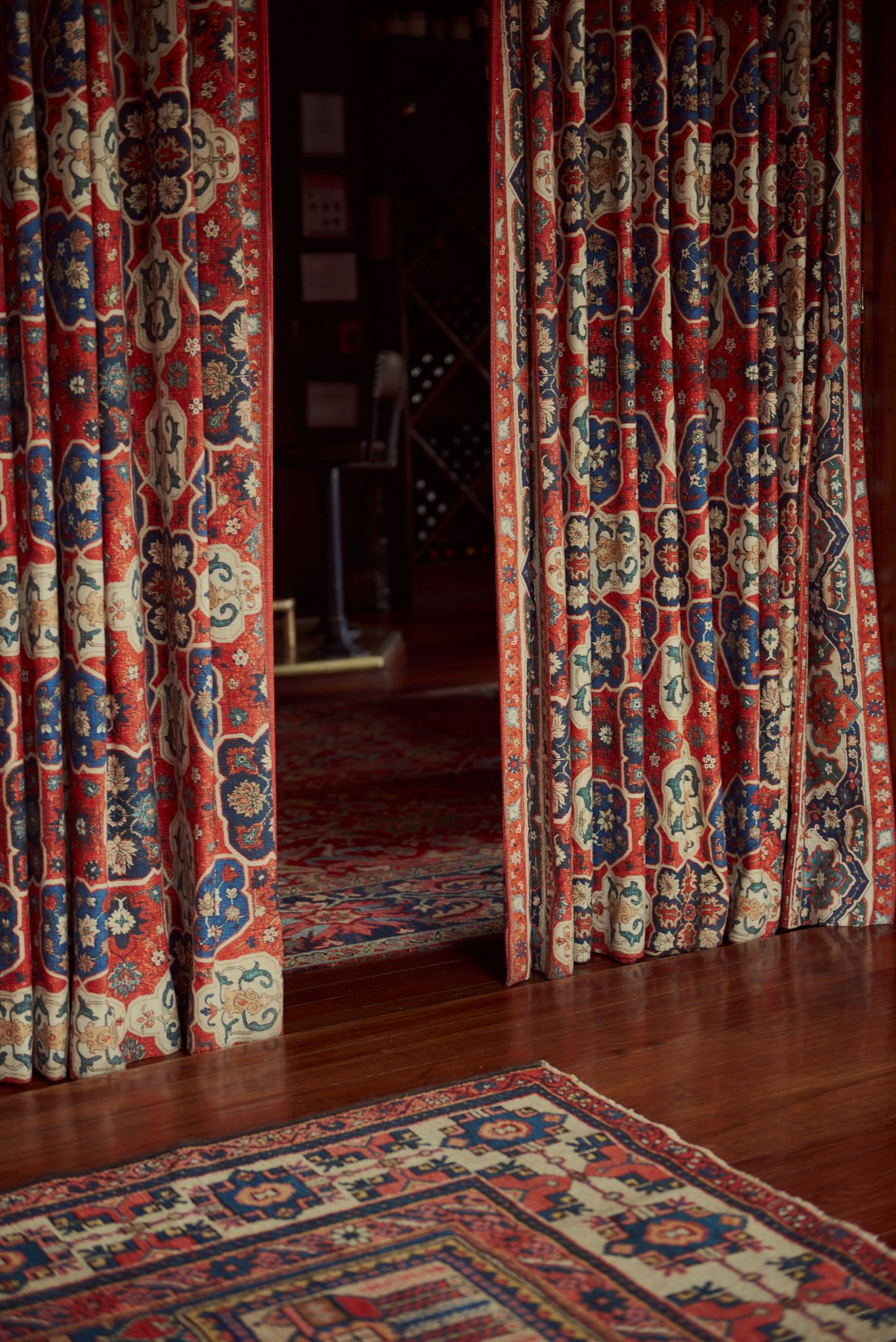 A room with red curtains and a rug on the floor.