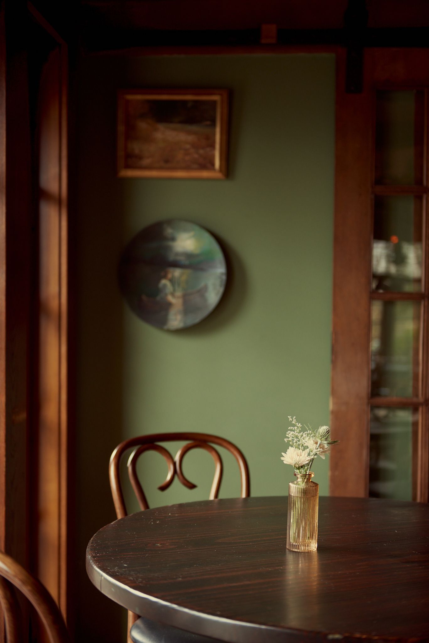 A table with a vase of flowers on it in a room with green walls.