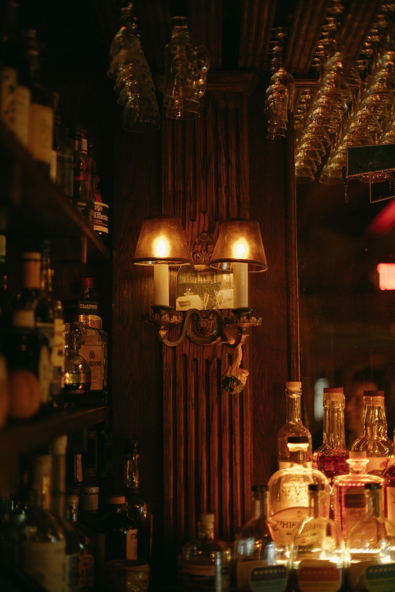 A bar with a lot of bottles and glasses on the shelf