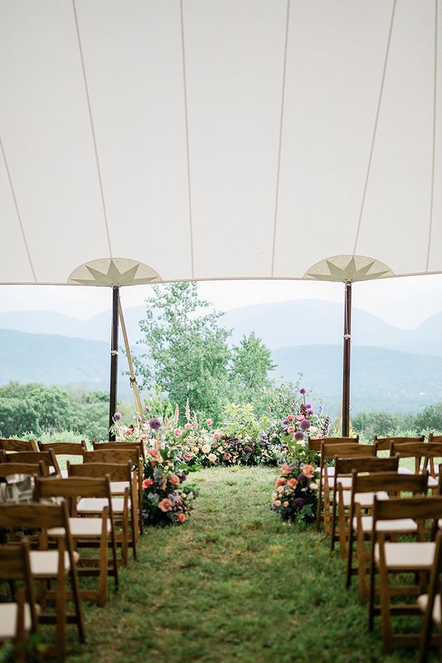 A wedding ceremony is taking place under a tent with a view of the mountains.