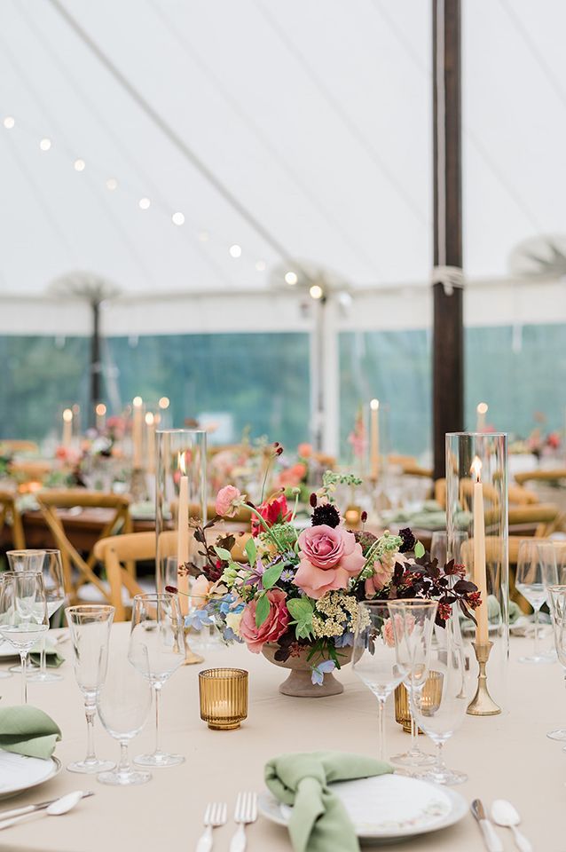 A table set for a wedding reception with a vase of flowers on it.