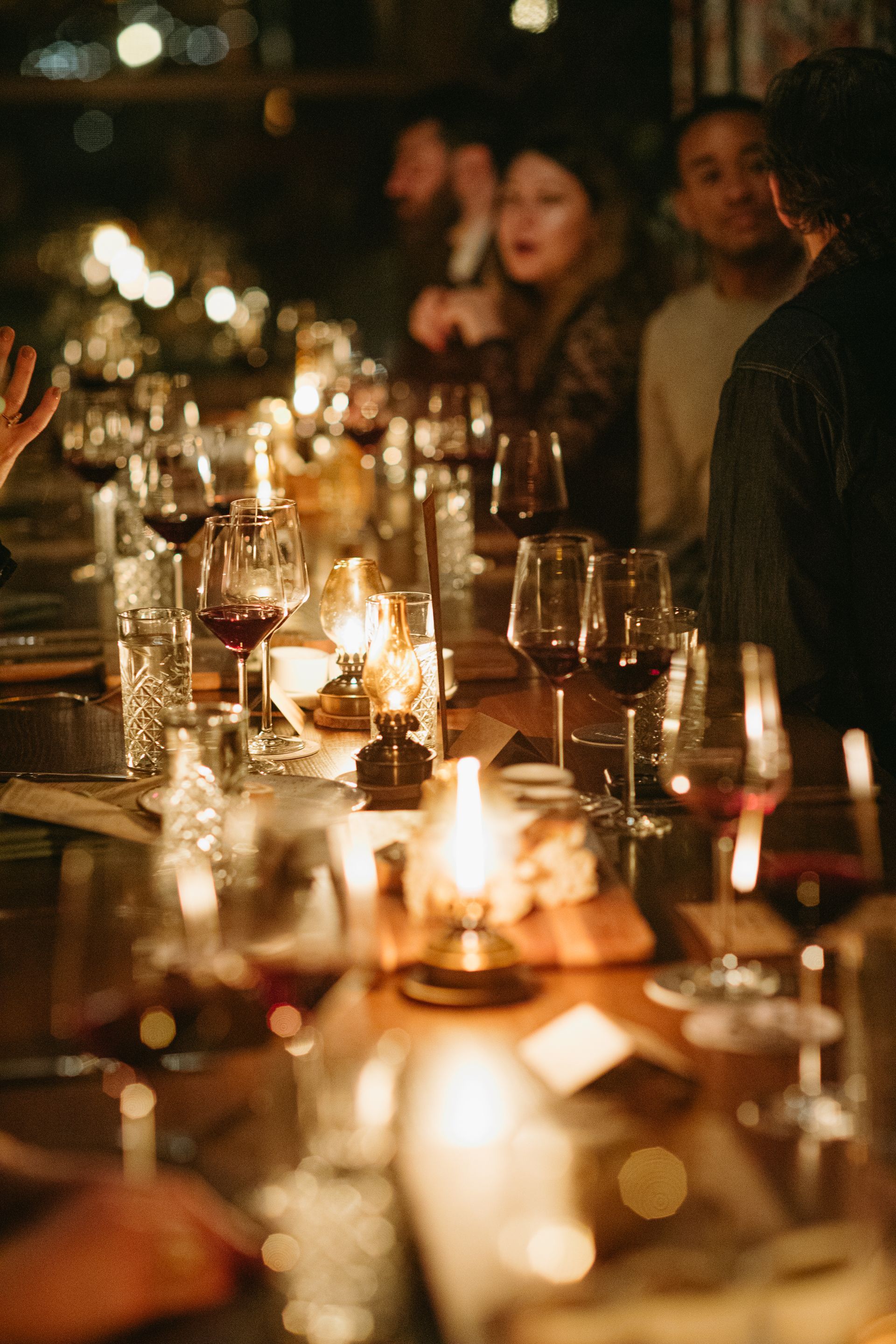 A group of people are sitting at a long table with wine glasses and candles.
