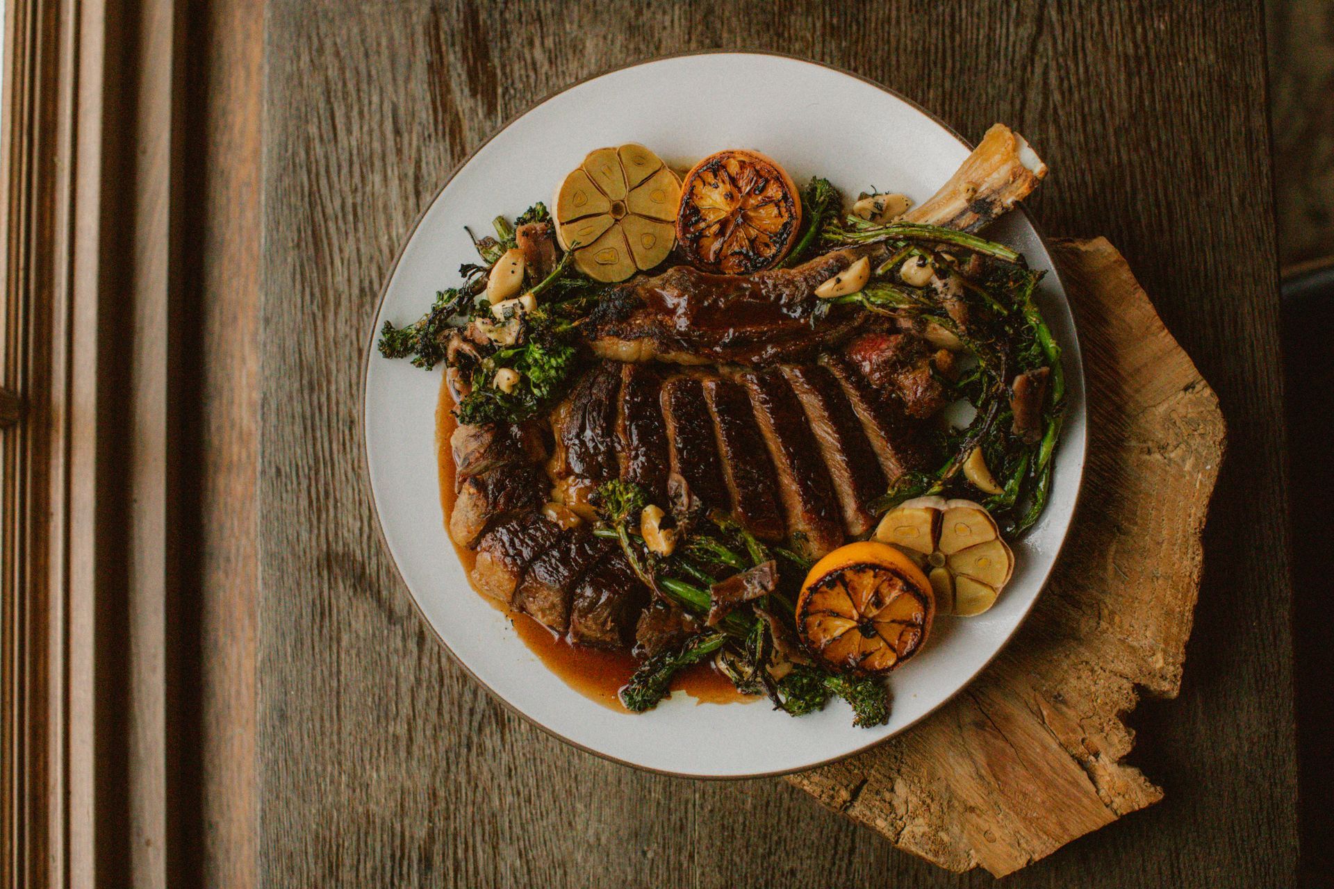 A white plate topped with meat and vegetables on a wooden table.