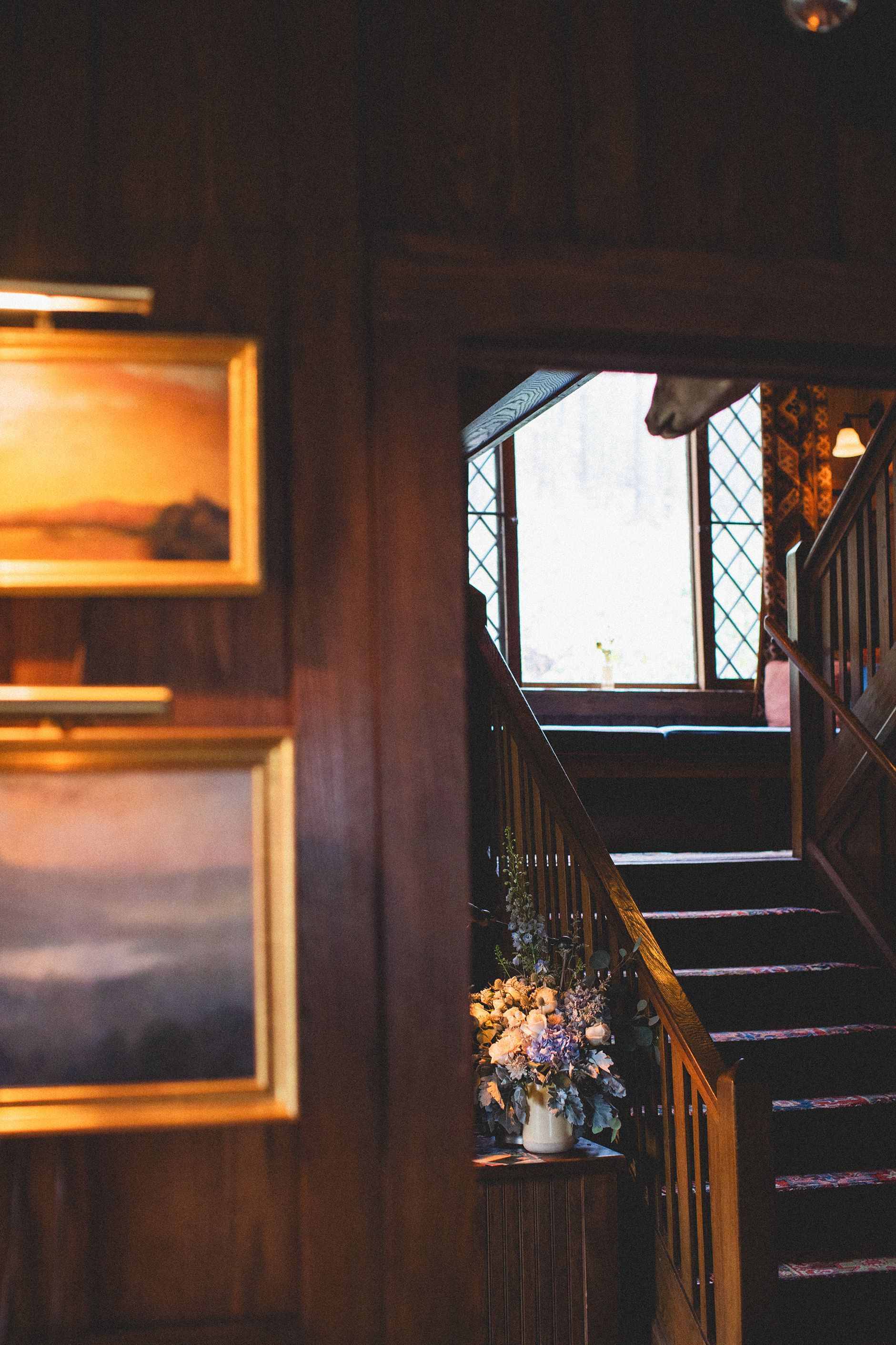 There are two paintings on the wall next to the stairs.