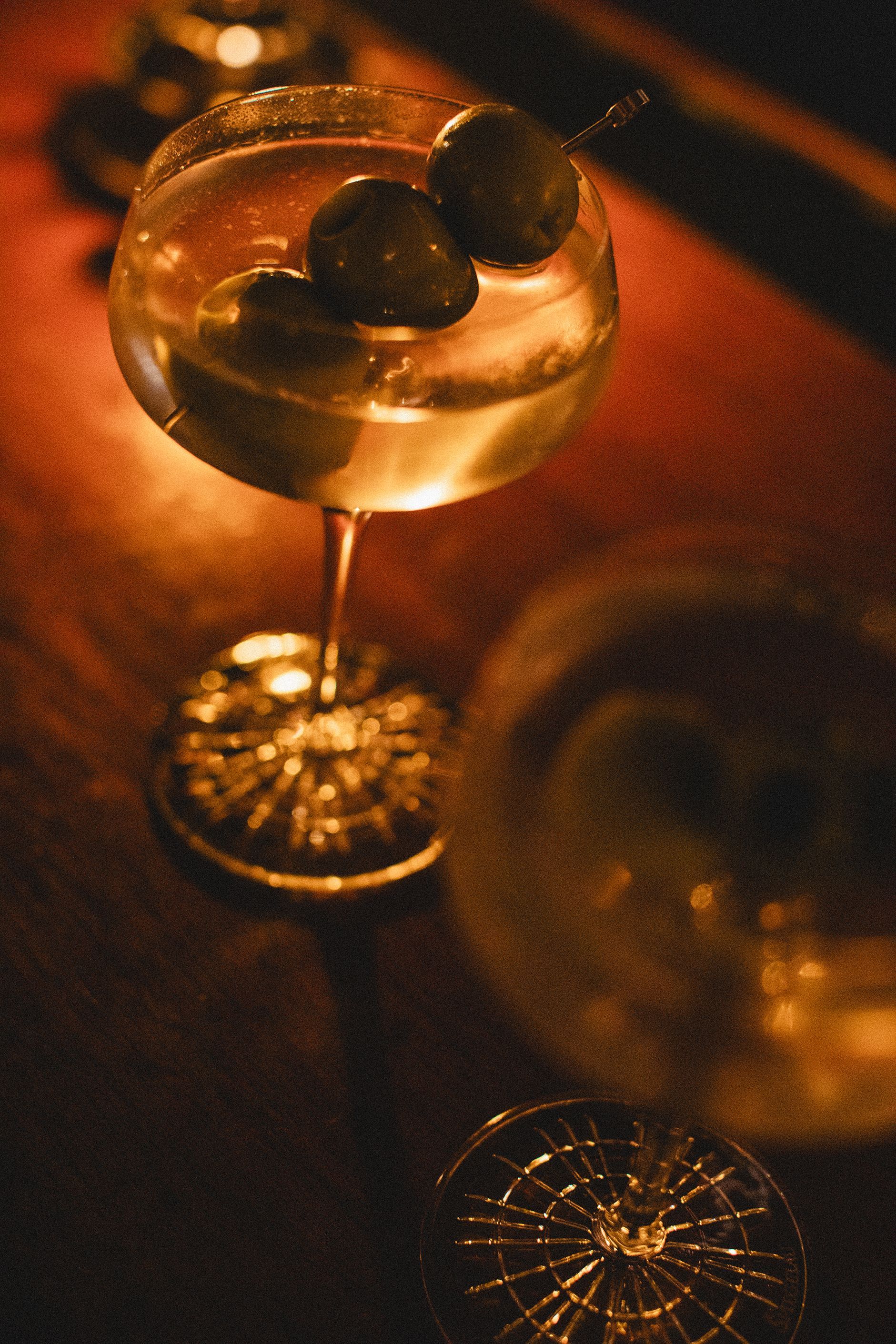 A martini with olives in it is on a table.