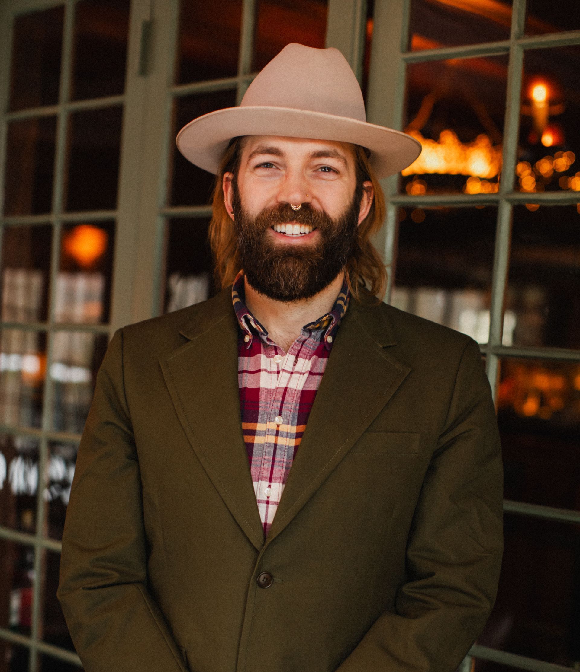 A man with a beard wearing a hat and a plaid shirt