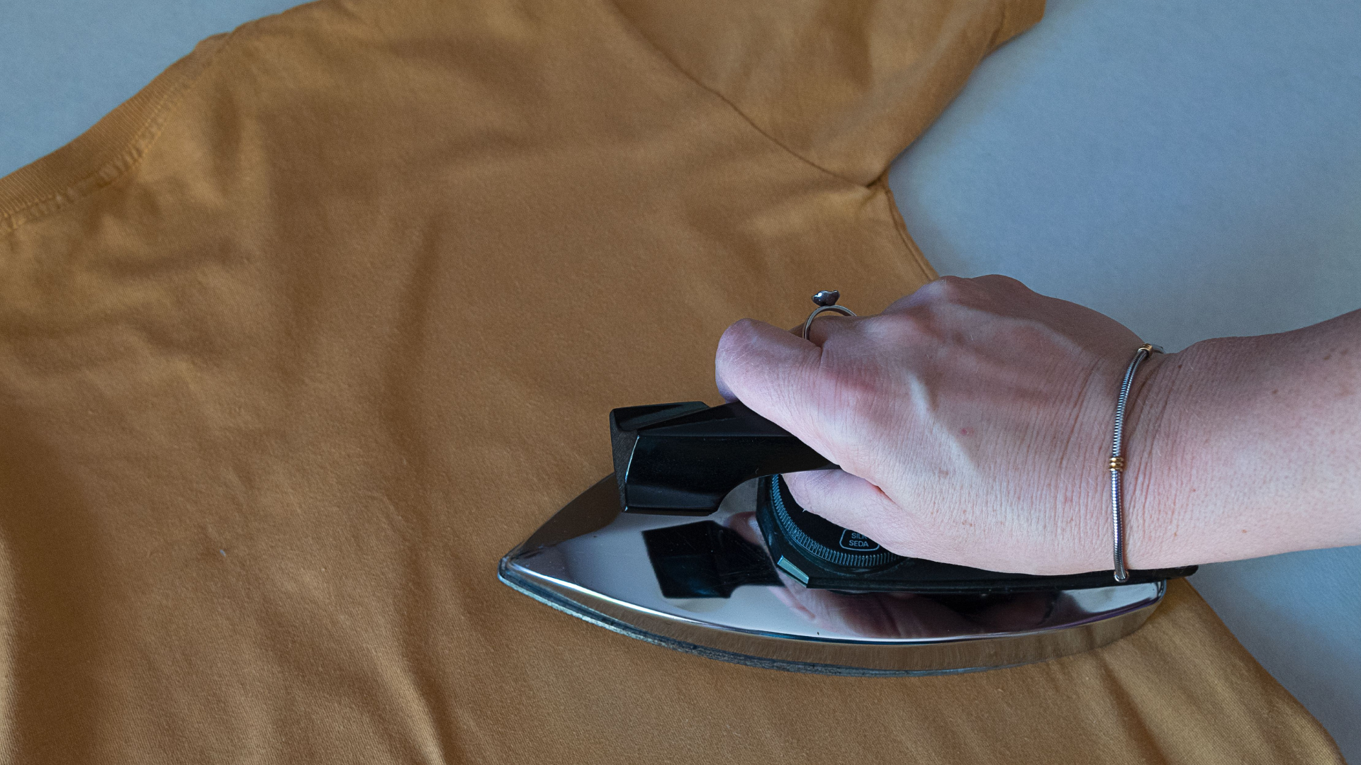 A person is ironing a piece of fabric with an iron.