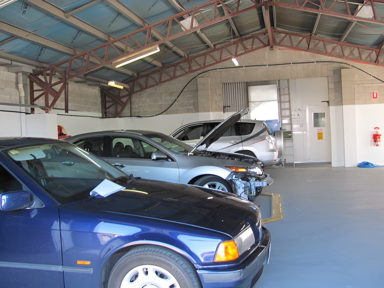 A Row of Cars Are Parked in a Garage With the Hoods Up — C & C Panel & Paint Mackay In Mackay, QLD