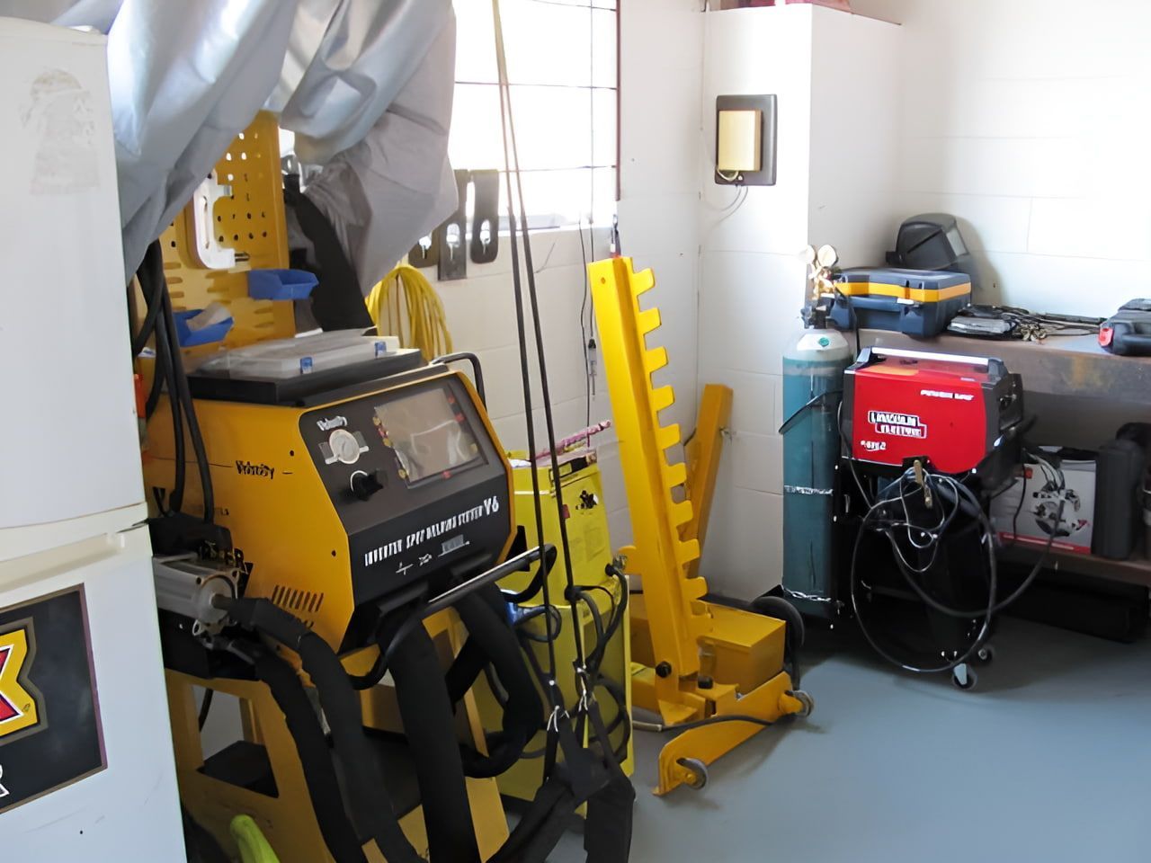 A Yellow Welding Machine is in a Room Next to a Refrigerator — C & C Panel & Paint Mackay In Mackay, QLD
