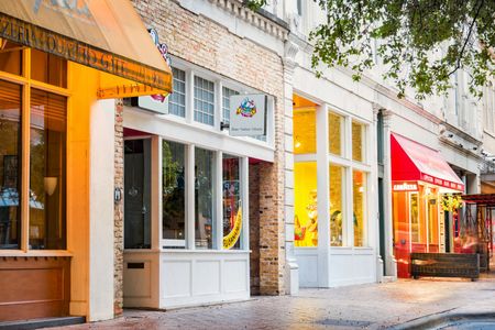 Row of shops with awnings and display windows. Sunlight reflects off the buildings.
