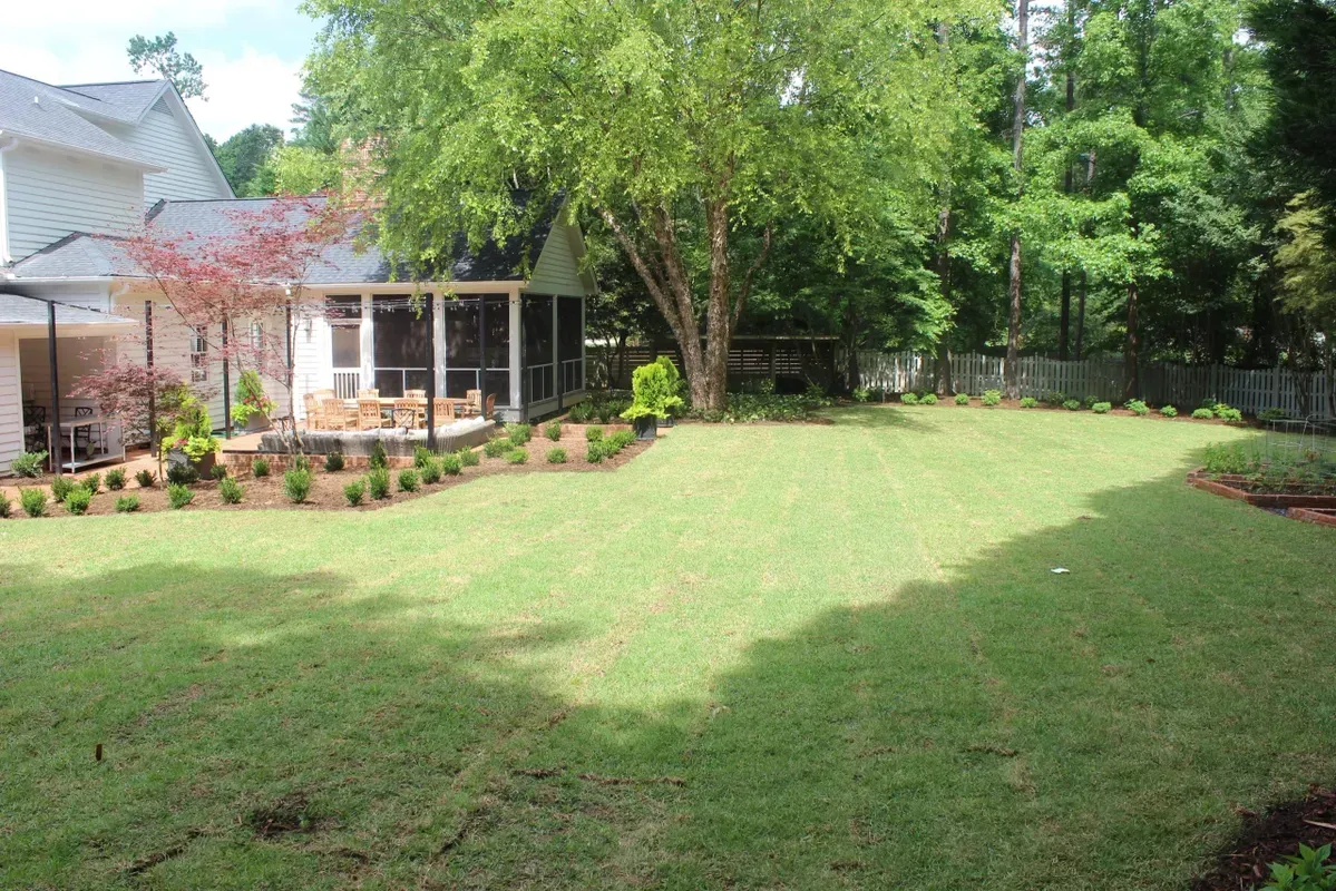 a large lawn in front of a house with a screened in porch .