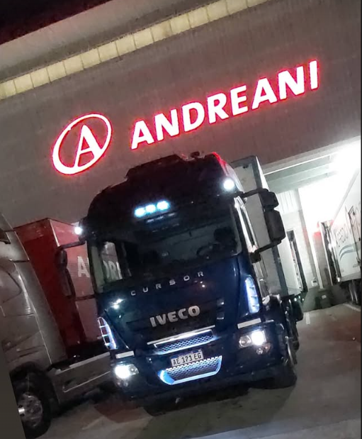 Camión Iveco azul estacionado bajo el letrero de Andreani en un muelle de carga.
