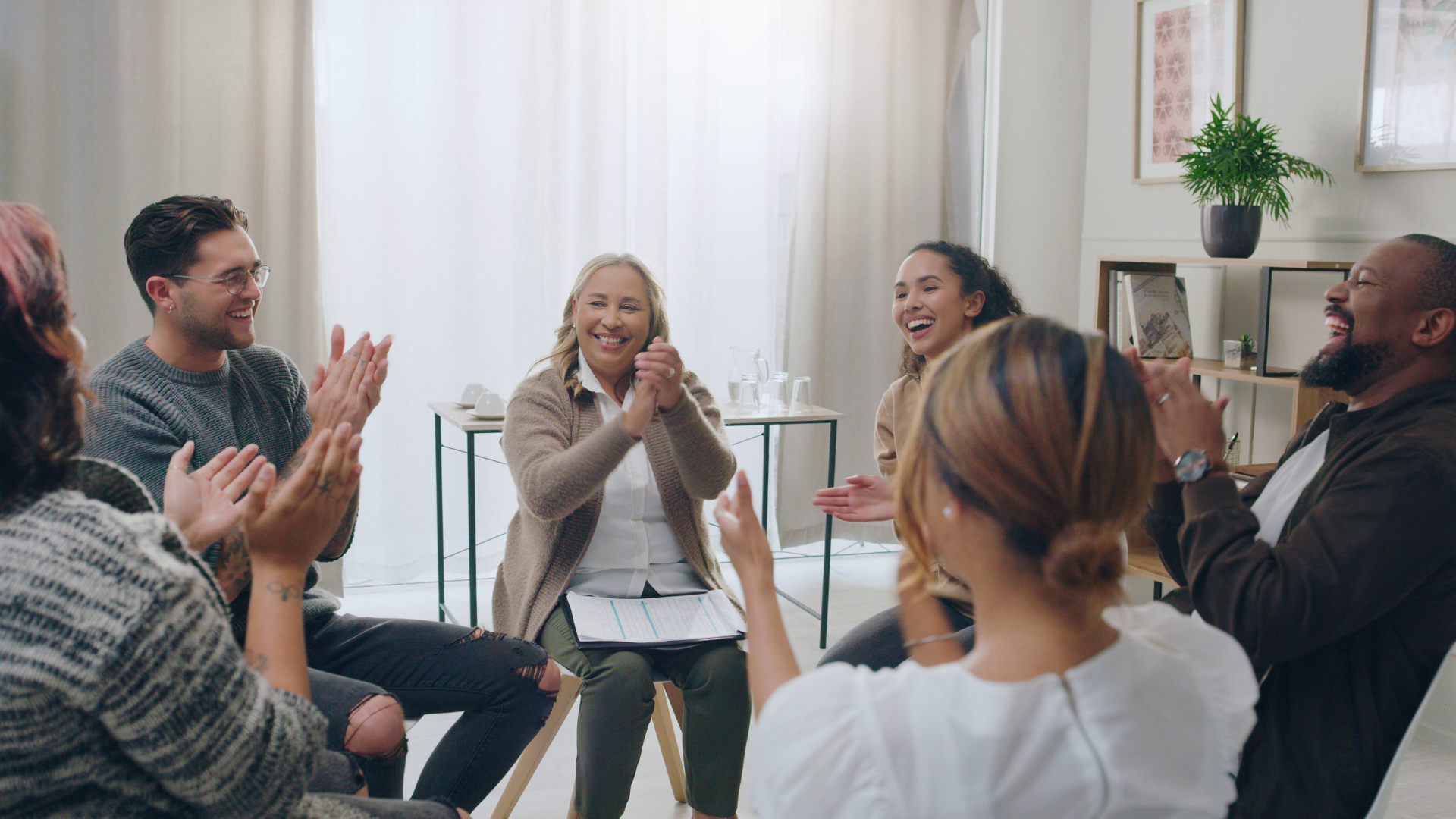 Group in a counseling session, seated in a circle, with one person speaking and others listening.