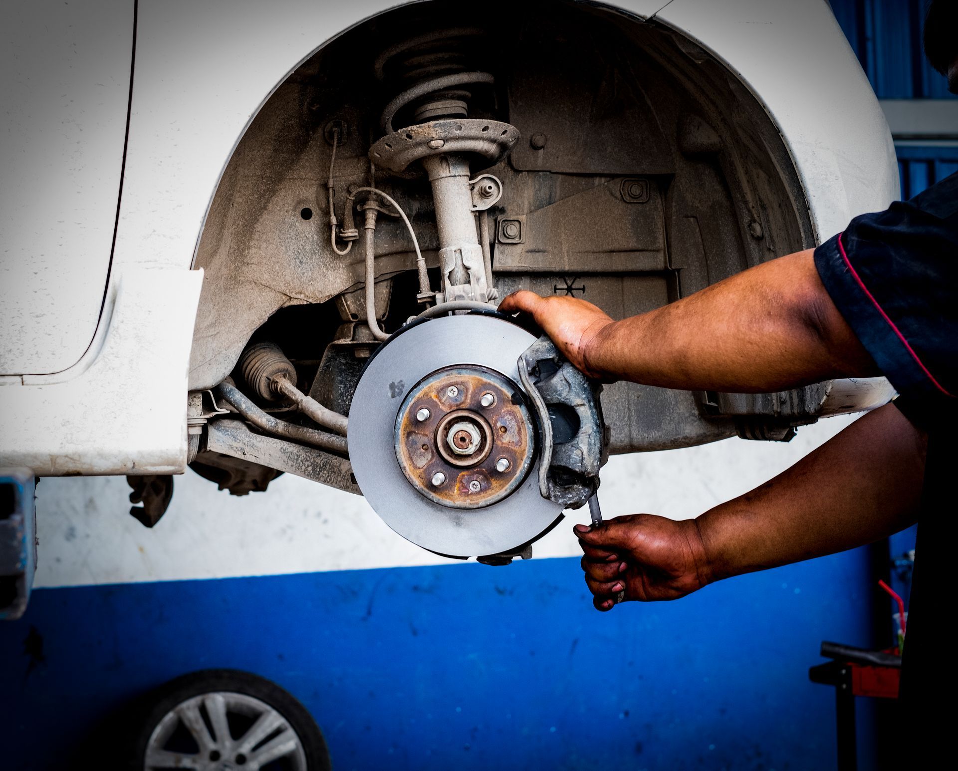 A man is working on a brake disc on a car