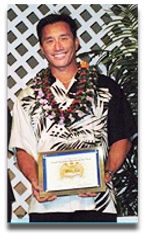 A man wearing a lei is holding a framed certificate.