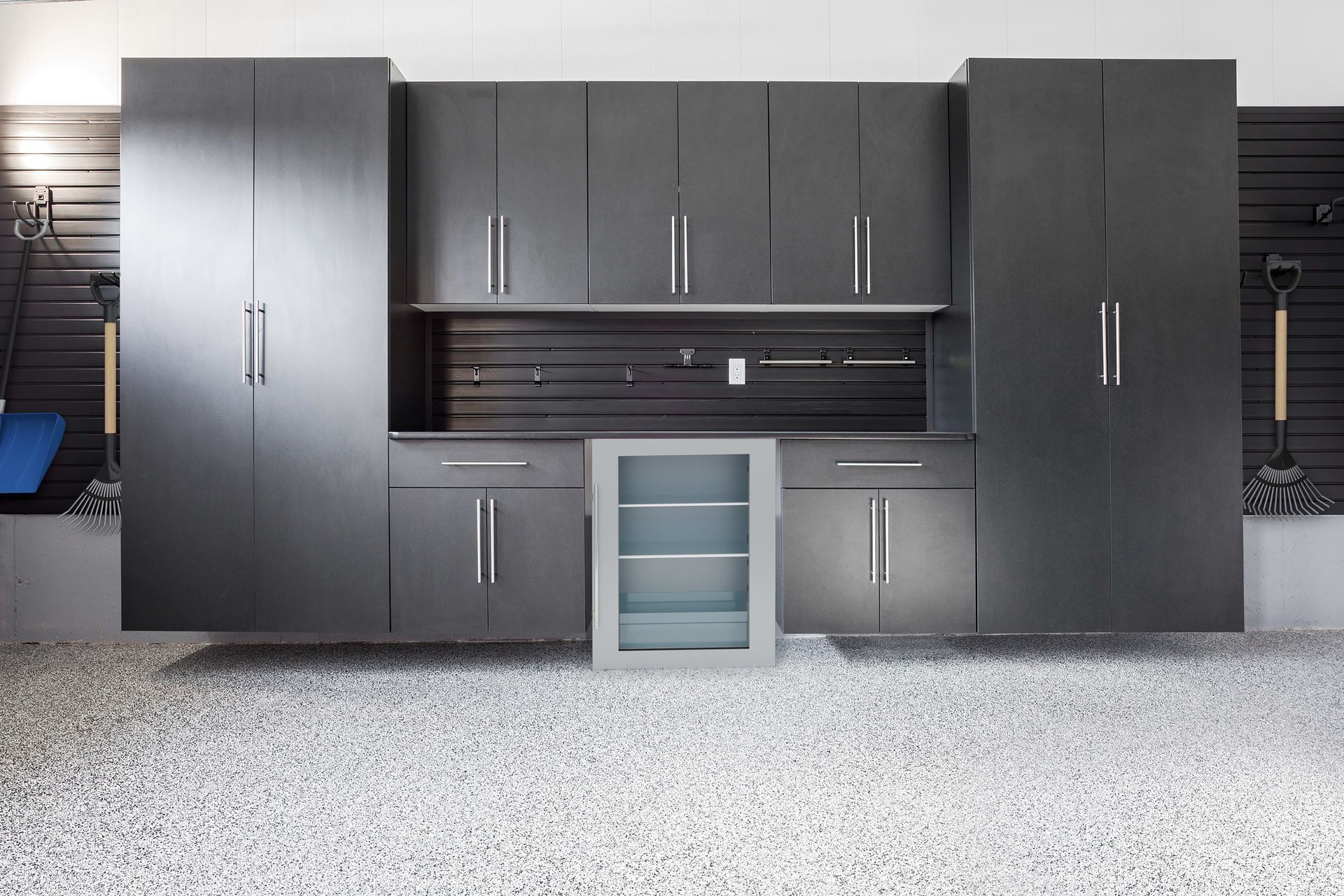 A garage filled with black cabinets and a refrigerator.