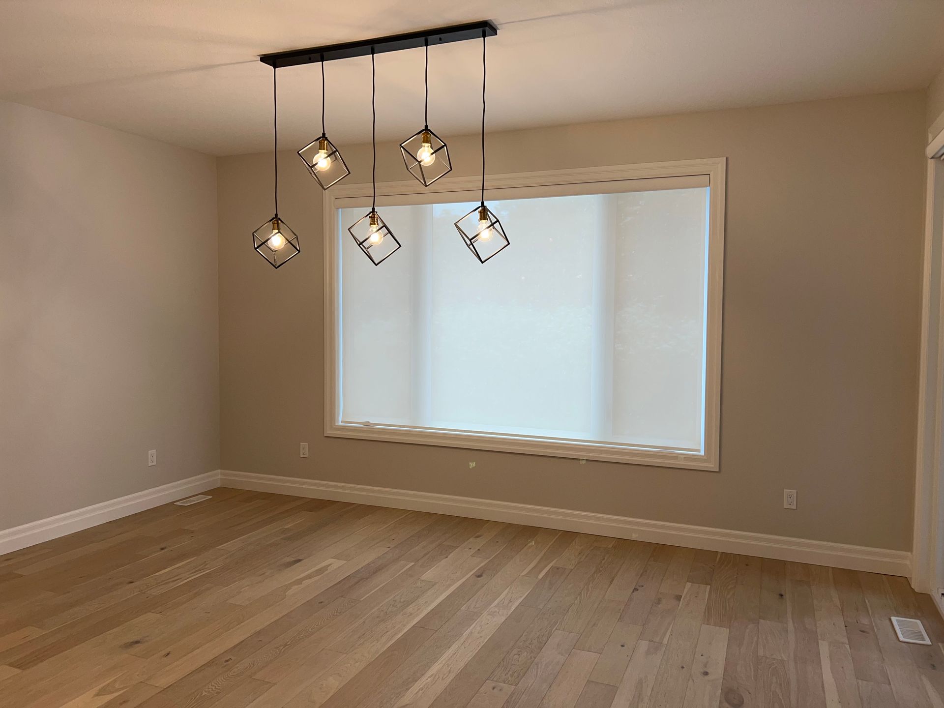 An empty room with hardwood floors and a large window.