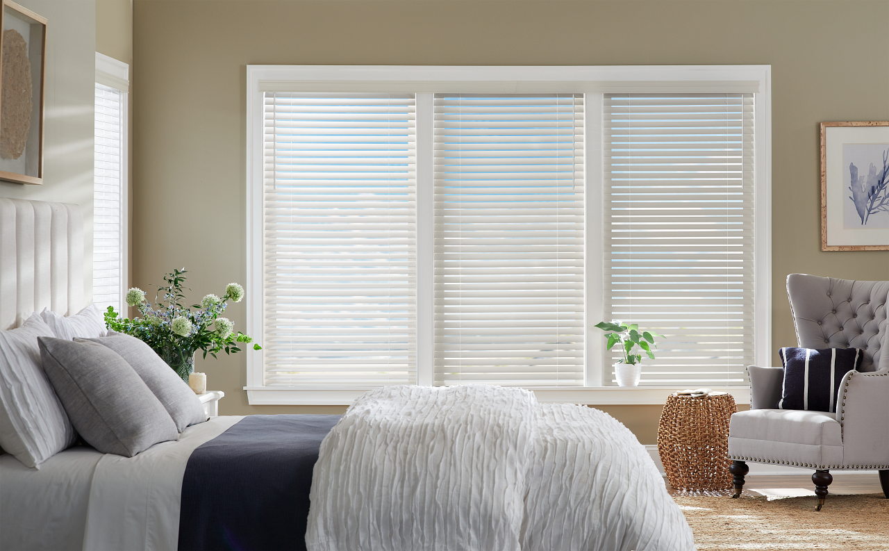 A bedroom with a bed , chair , and window with blinds.