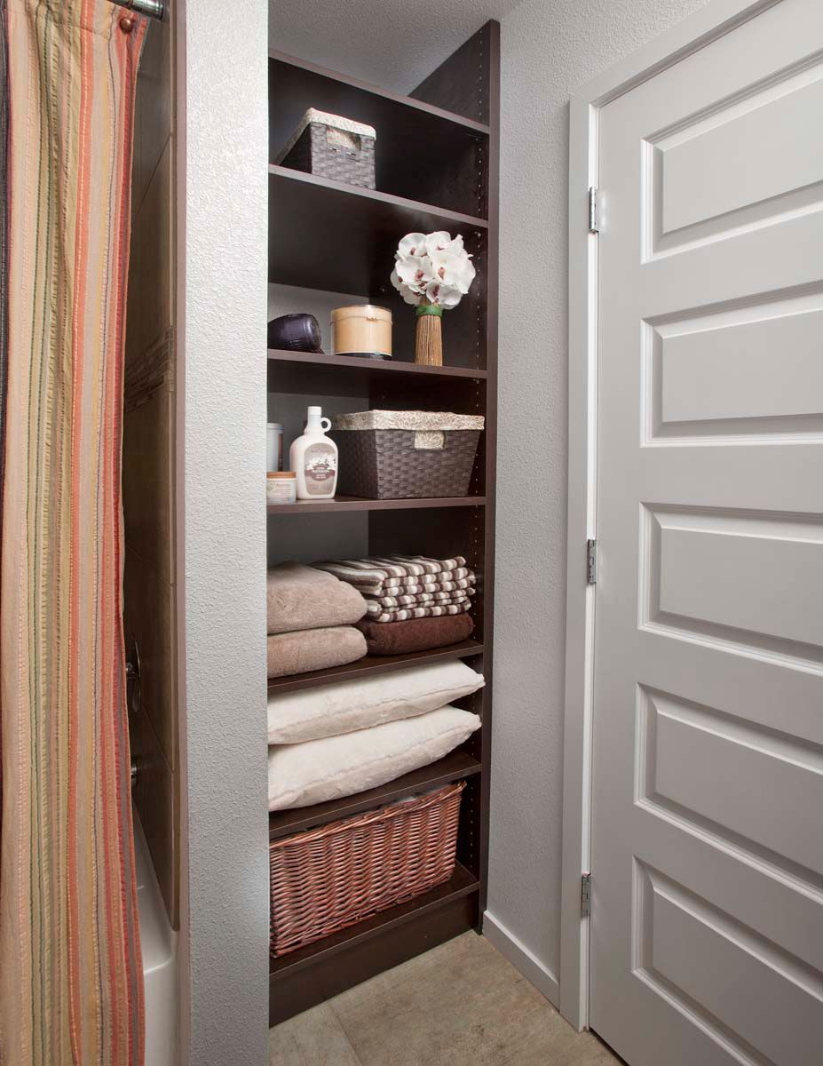 A closet with shelves and baskets filled with pillows and blankets