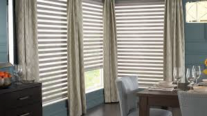 A dining room with a table and chairs and blinds on the windows.