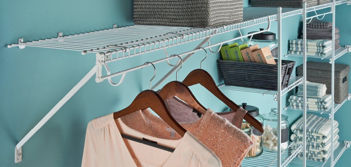 A closet with clothes hanging on a rack and baskets.
