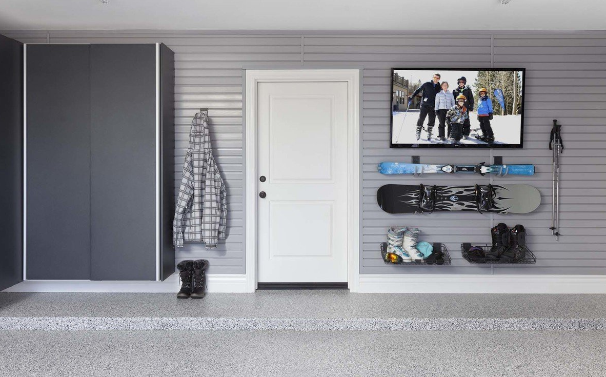A garage with a tv on the wall and snowboards on the shelves.