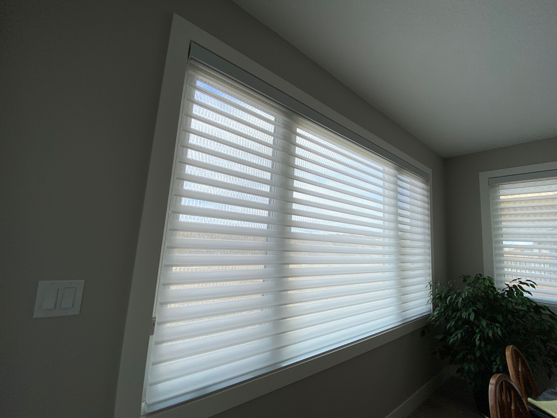 A large window with white blinds in a living room.