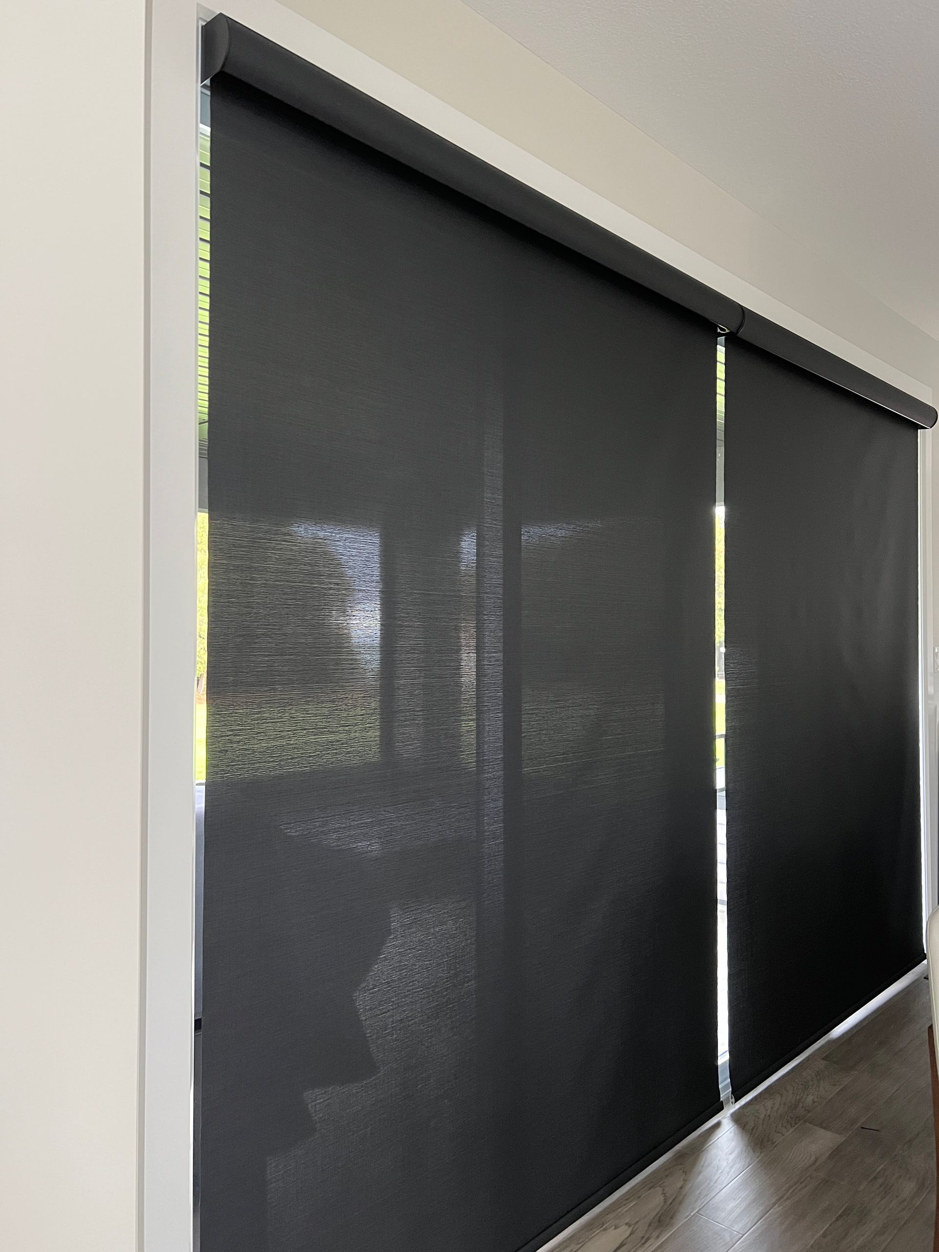 A living room with black blinds on the windows.