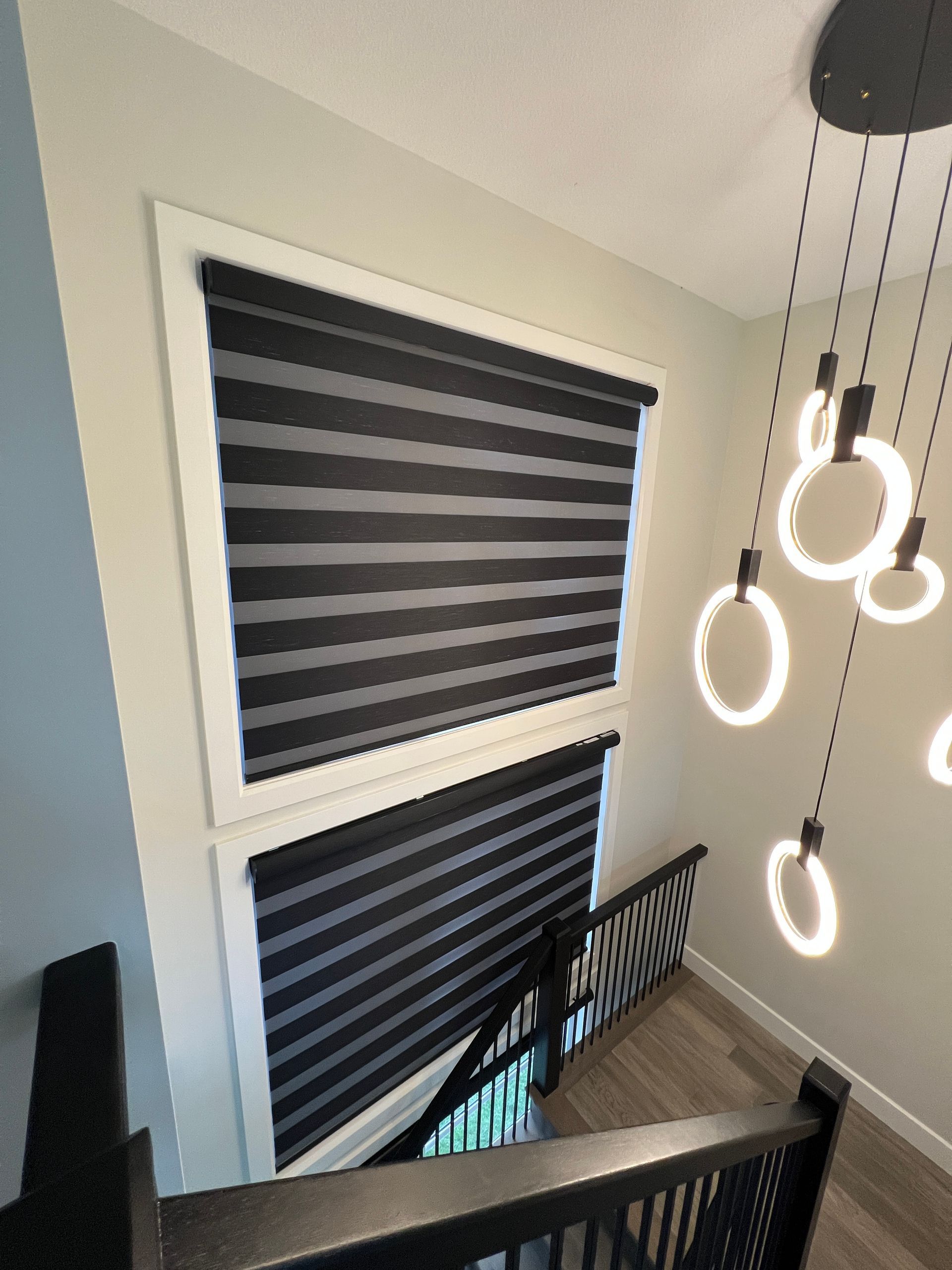 A view of a staircase from the second floor with blinds on the windows.