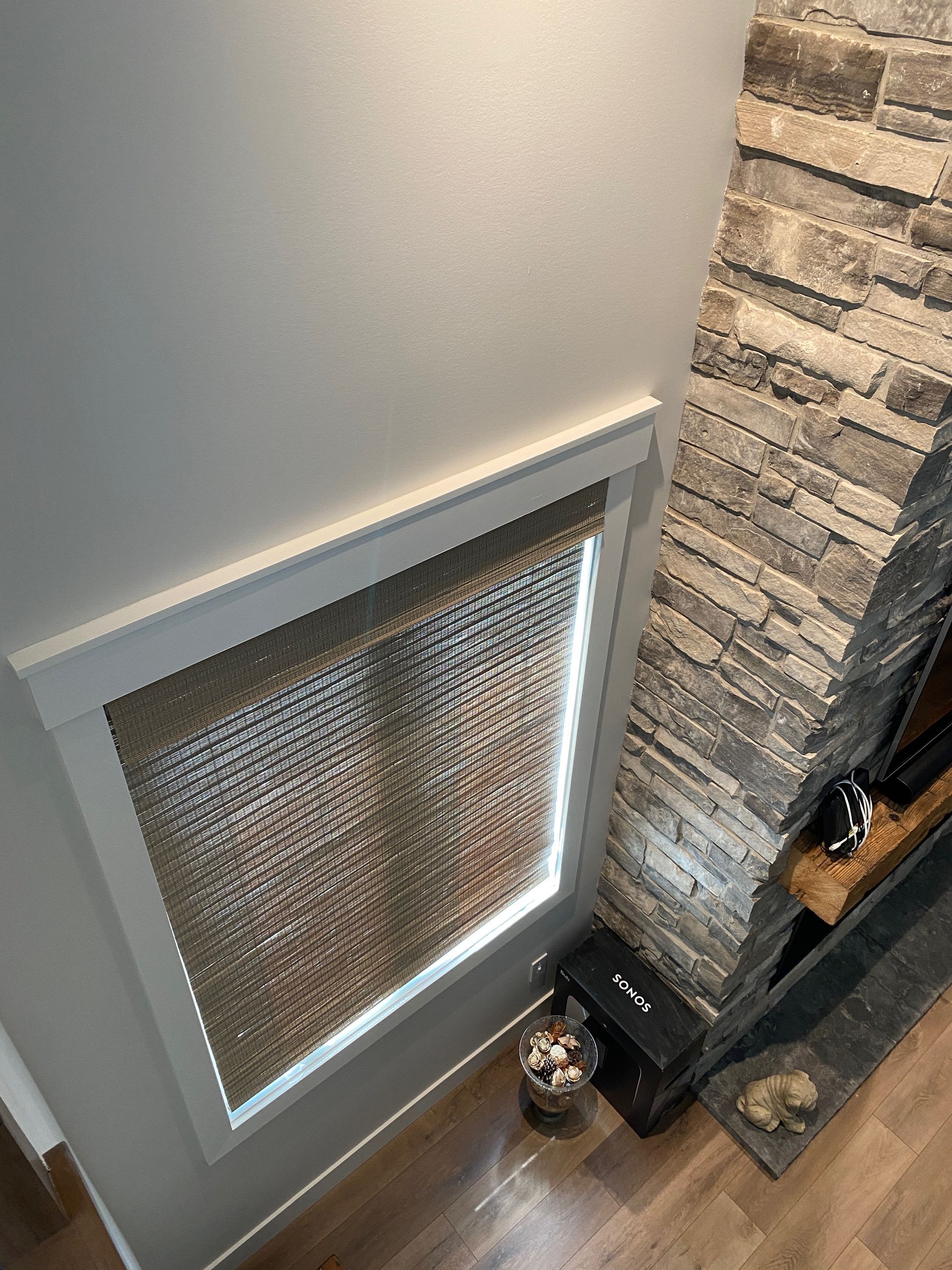 A living room with a fireplace and a window with blinds.