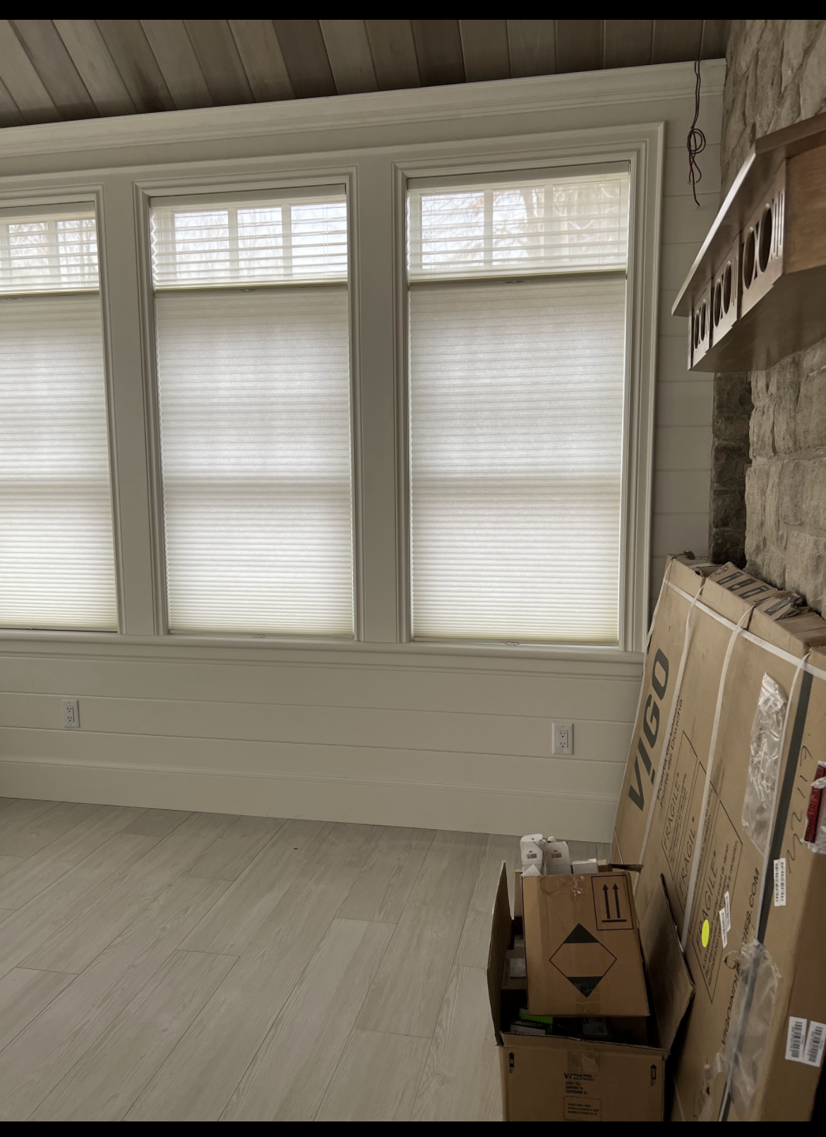 A living room with boxes stacked on the floor and a fireplace.