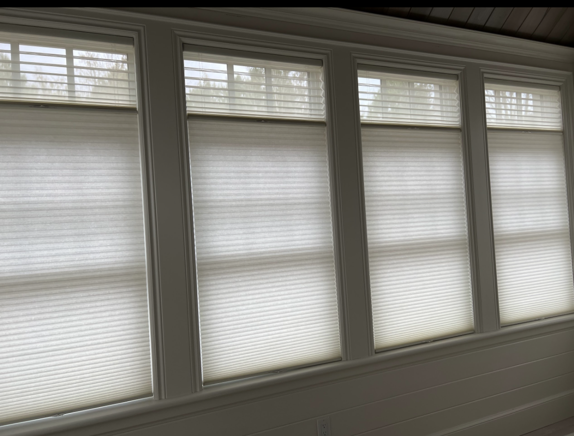 A room with a lot of windows with white blinds on them.