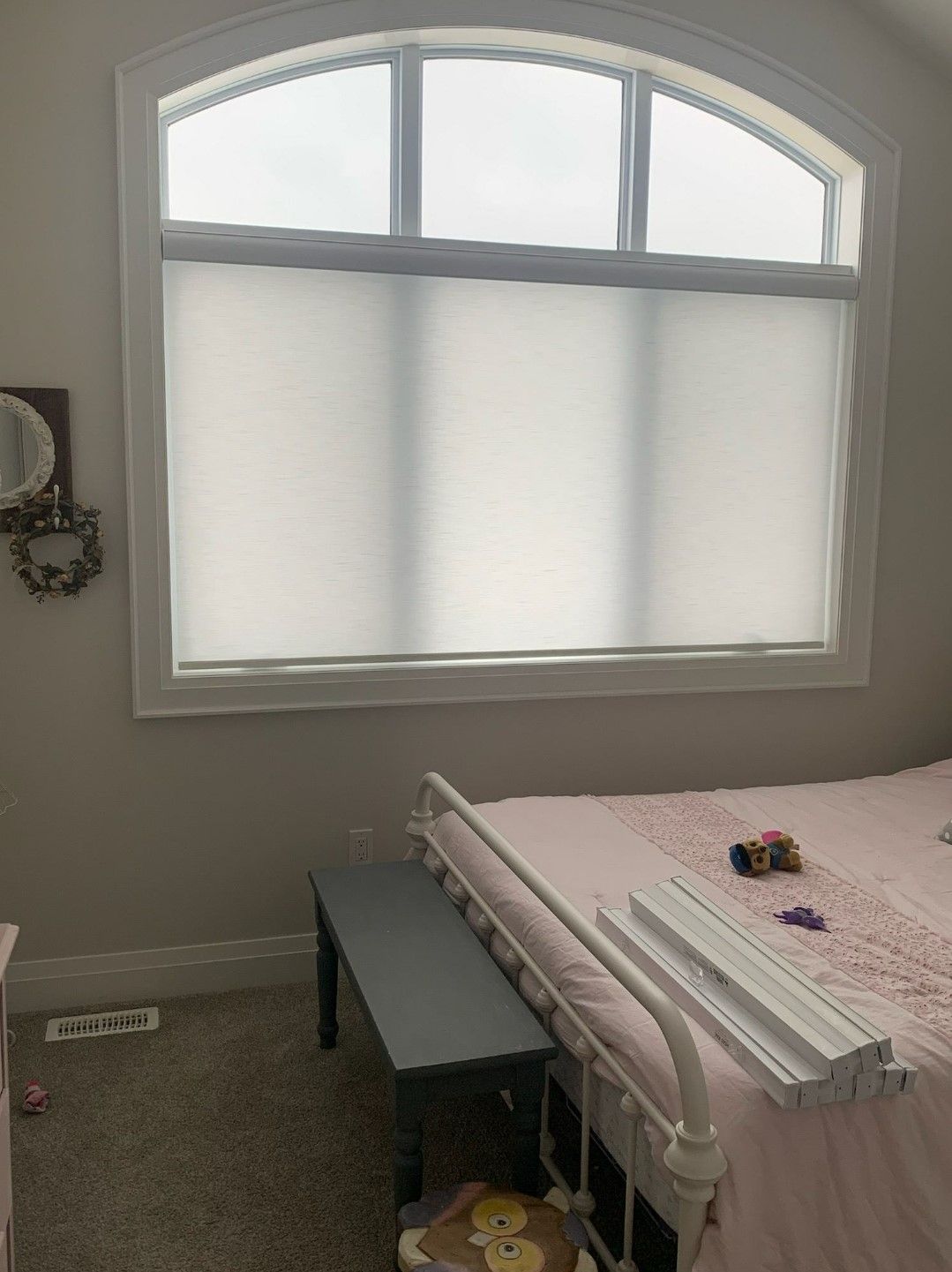 A bedroom with a bed and a window with white blinds.