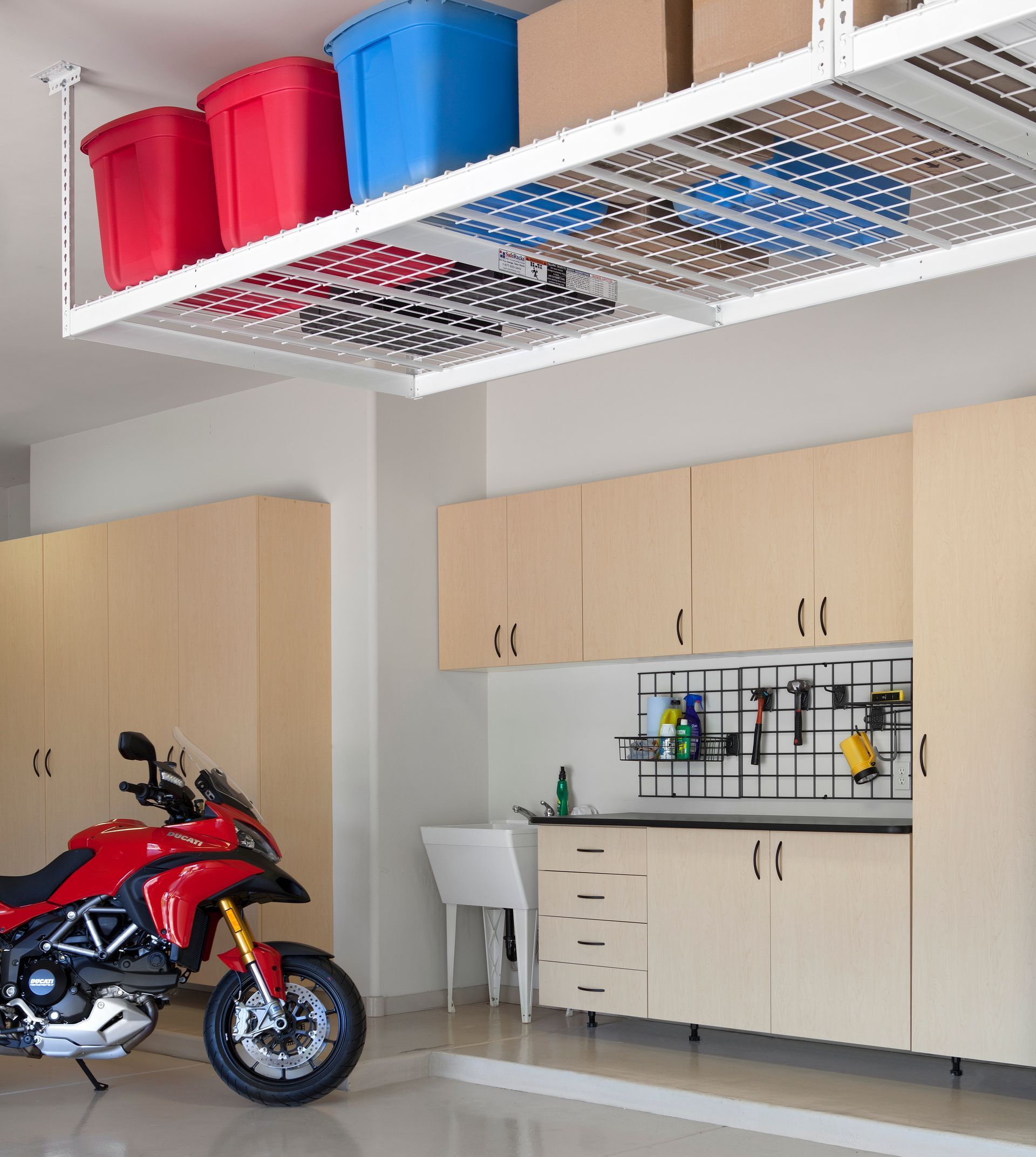 A motorcycle is parked in a garage under a shelf with boxes on it