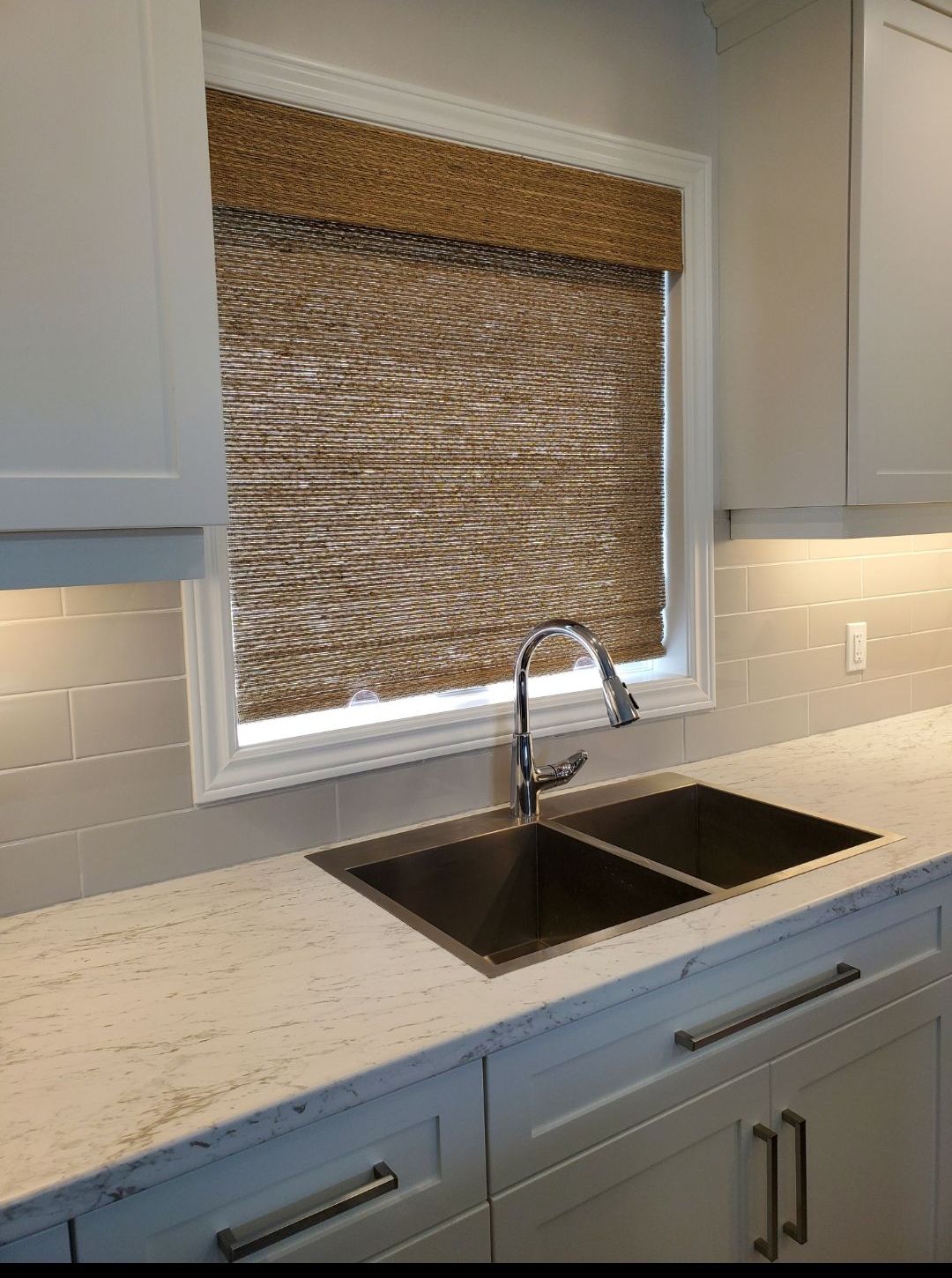 A kitchen with a sink and a window with blinds.