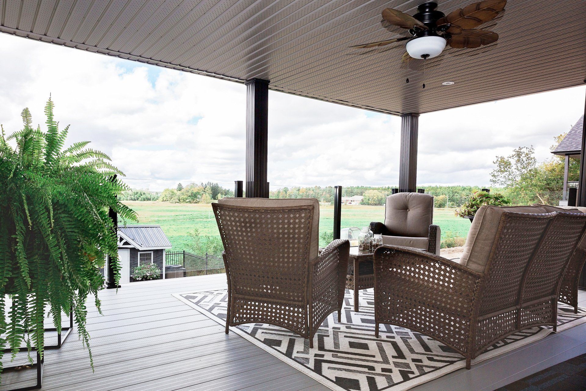 A patio with wicker furniture and a ceiling fan.