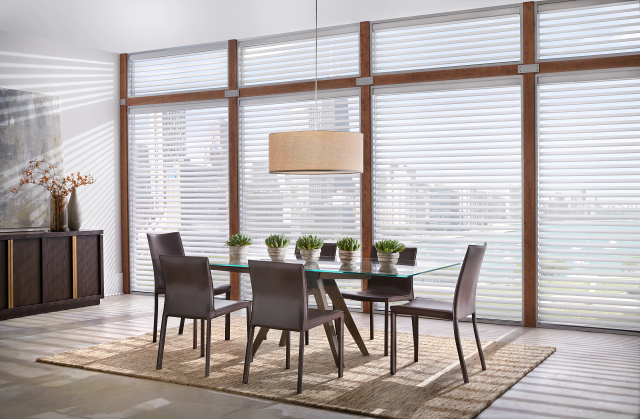 A dining room with a table and chairs in front of a large window.
