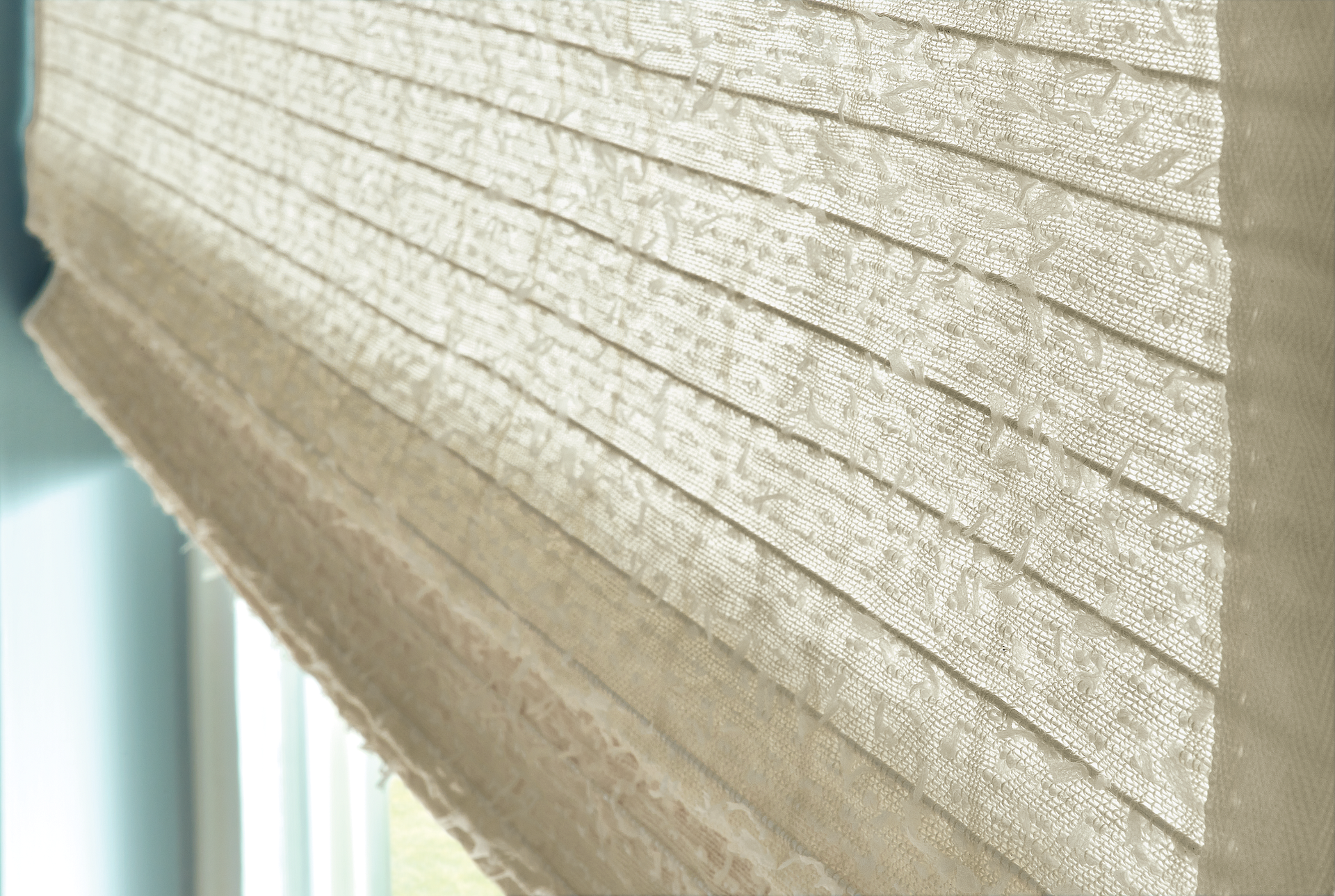 A close up of a roman shade on a window.