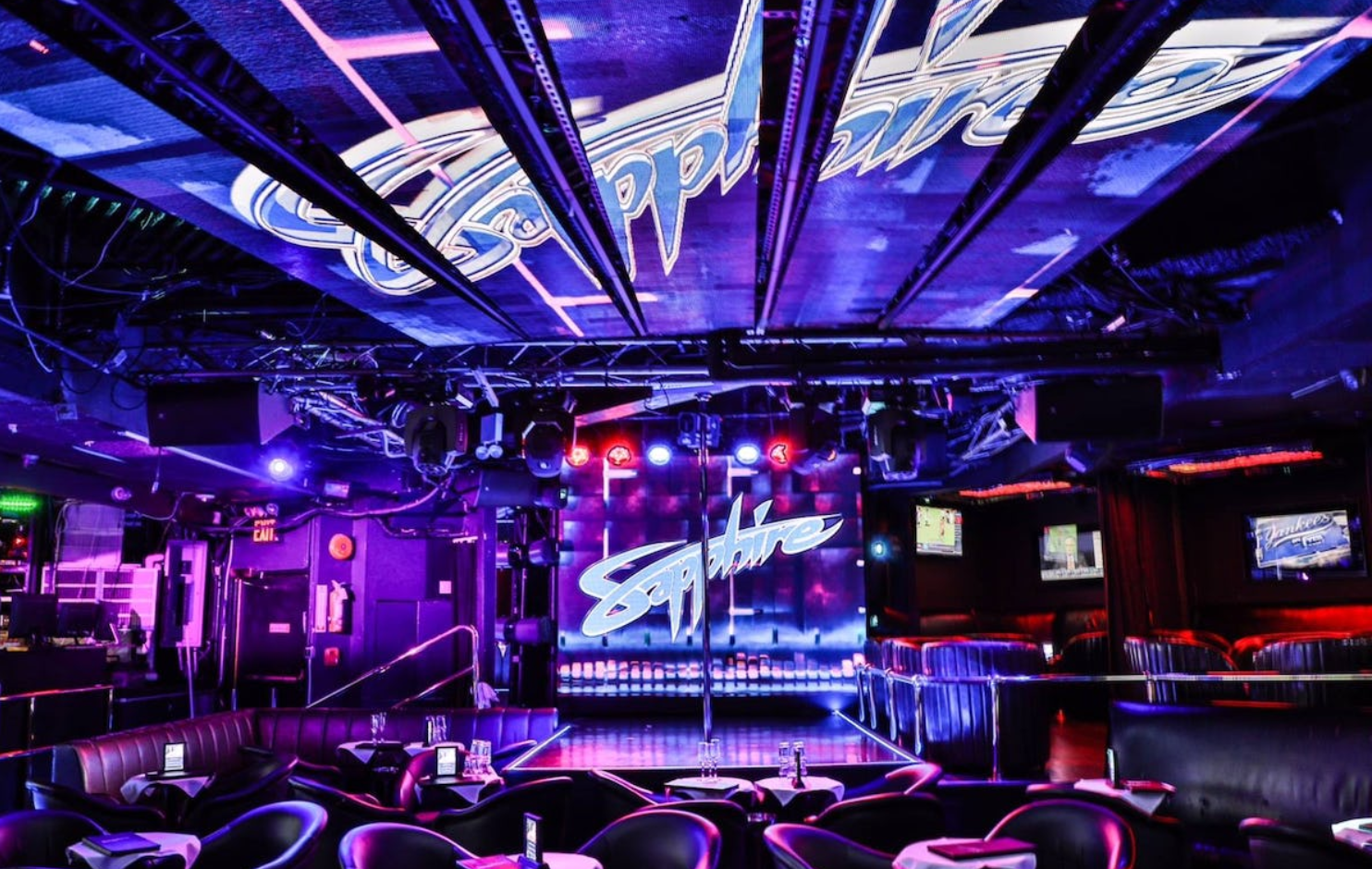 A nightclub with purple lights and a pole in the middle