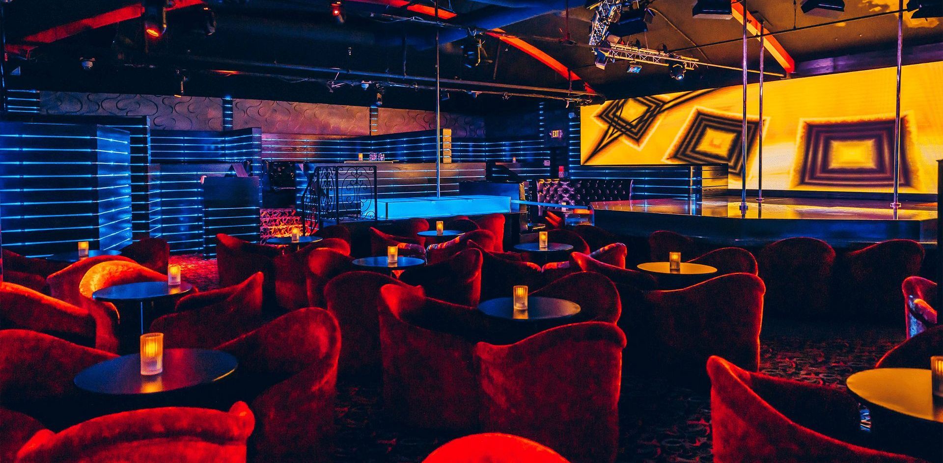 A nightclub with tables and chairs and a stage.