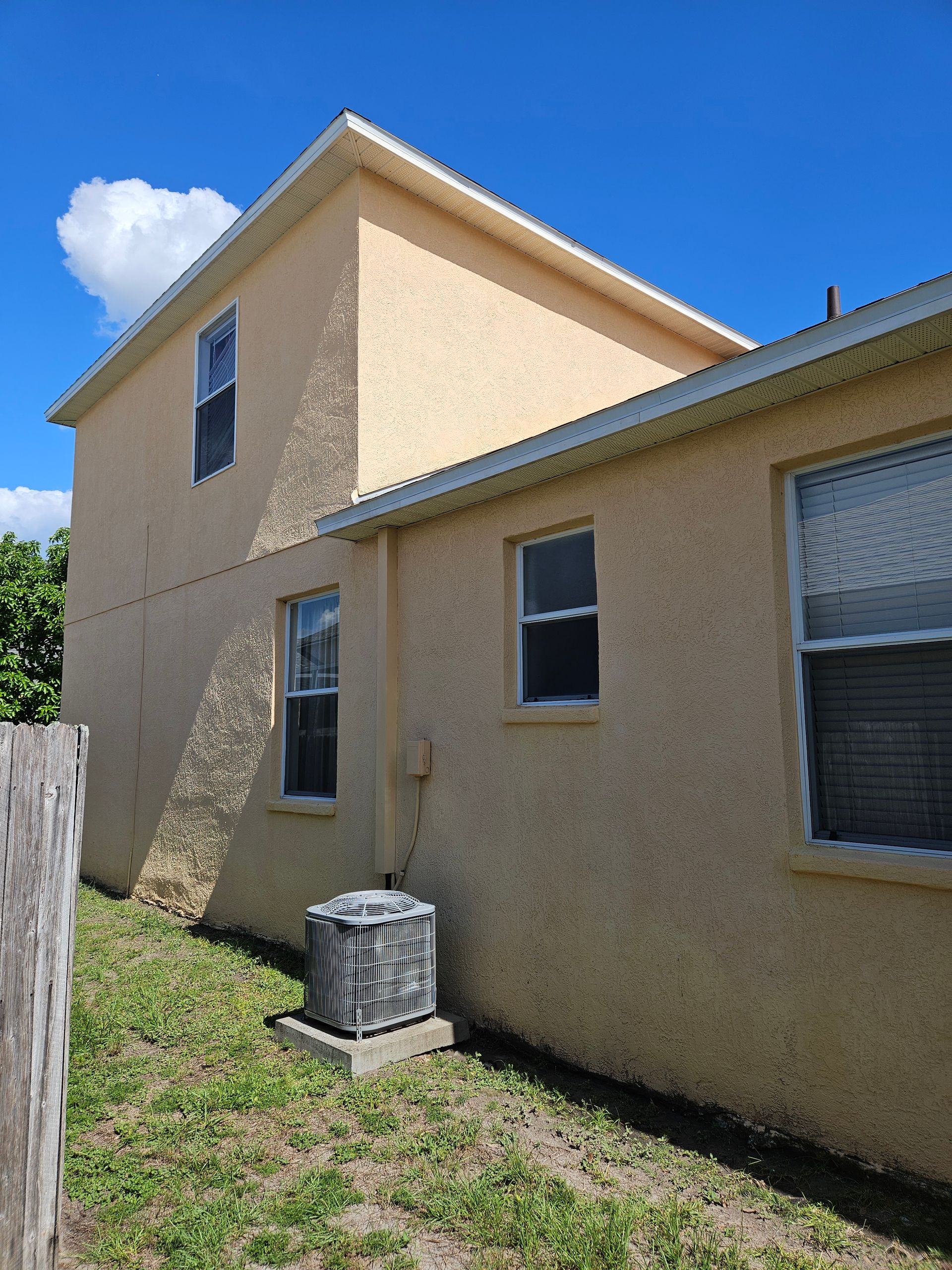 A house with a lot of windows and a fence in the backyard.